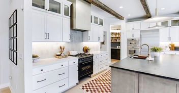 Image of kitchen remodel with modern white cabinets, black range, and farmhouse style island in Oakland County, MI by Cabinet Creations