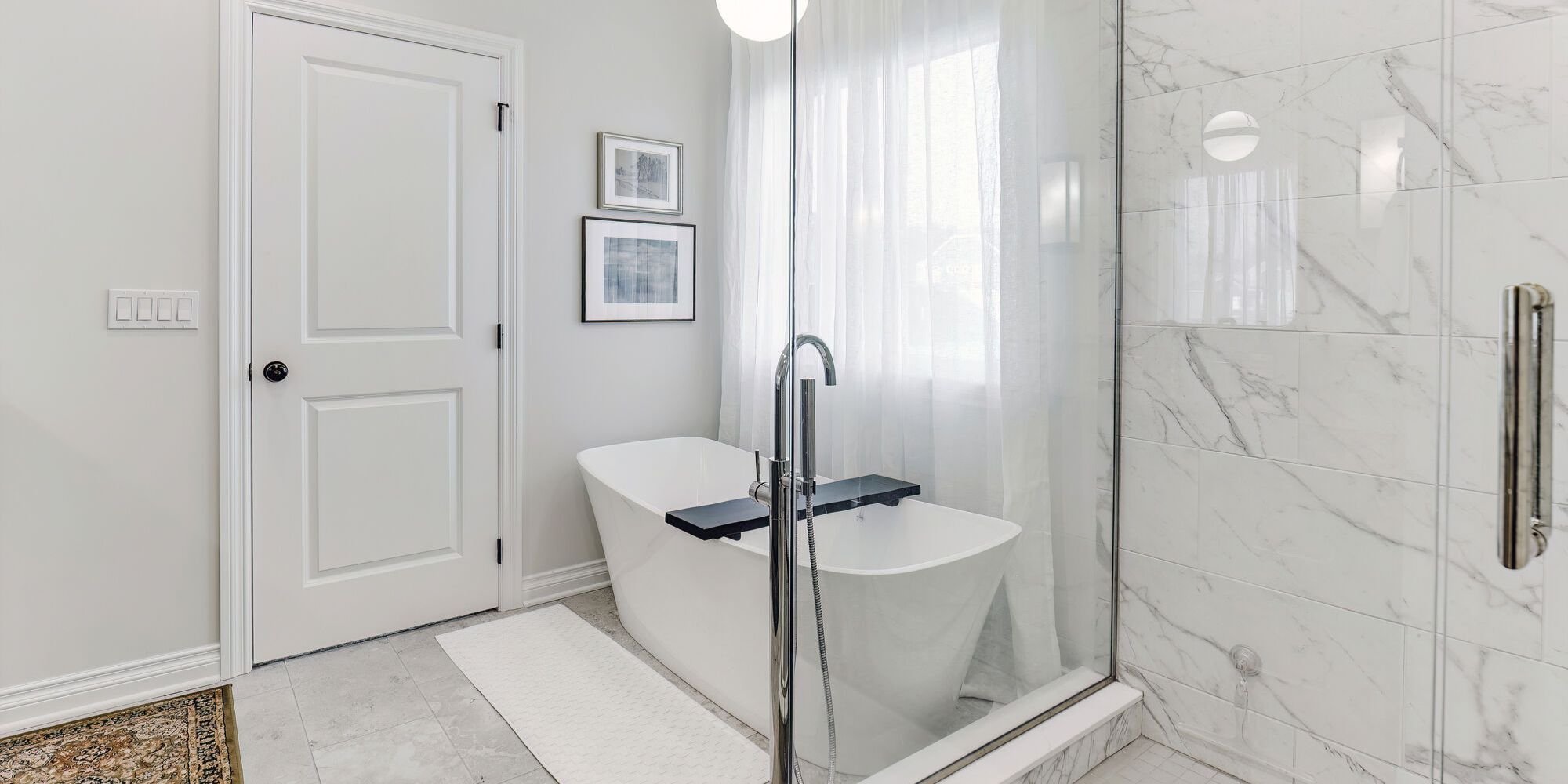Large glass shower and soaking tub combo with natural lighting in a custom bathroom by Cabinet Creations in Michigan