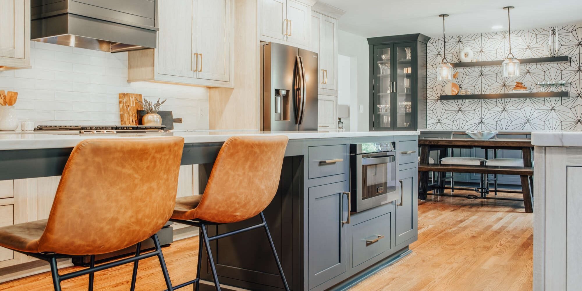 Two-tone custom kitchen remodel with modern island and leather bar stools by Cabinet Creations in Clarkston, Michigan