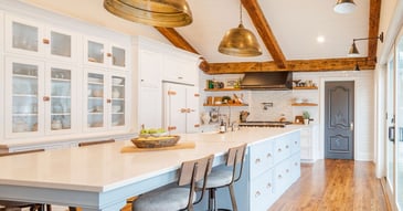 Bright kitchen remodel with blue island, glass cabinets, and exposed wood beams by Cabinet Creations in Oakland County