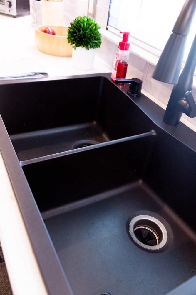 Black double-basin kitchen sink with modern faucet designed by Cabinet Creations in Bloomfield Hills, MI