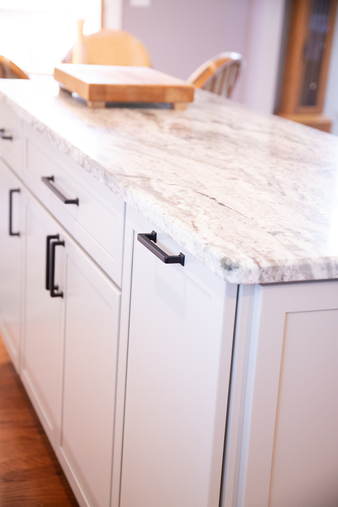 Bright kitchen island with white cabinetry and marble countertop in a custom home by Cabinet Creations in Oakland County, MI