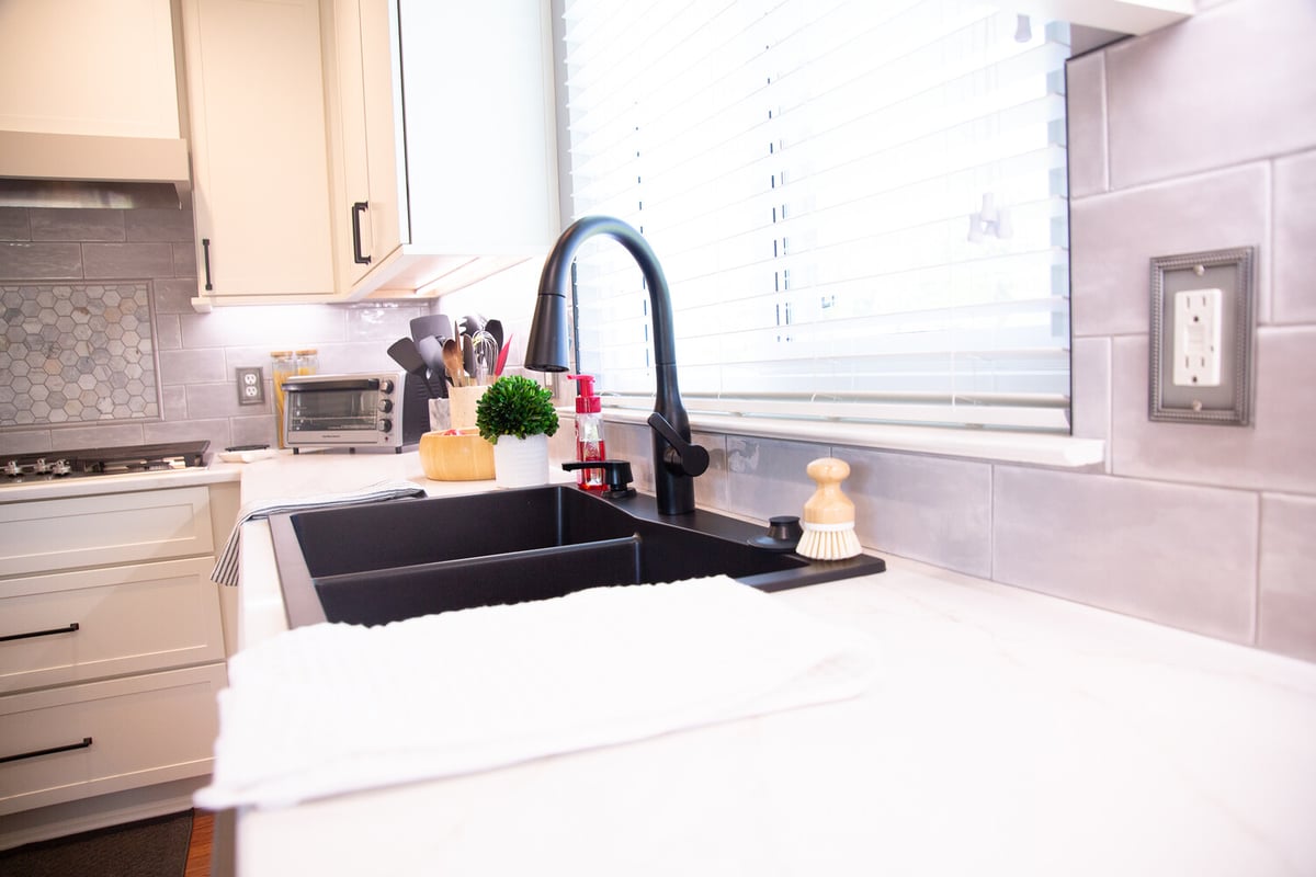 Bright kitchen with black sink, white counters, and tile backsplash by Cabinet Creations in Oakland County, MI