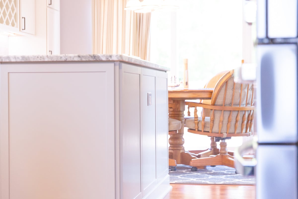 Custom kitchen island with marble countertop next to dining area by Cabinet Creations in Auburn Hills, Michigan