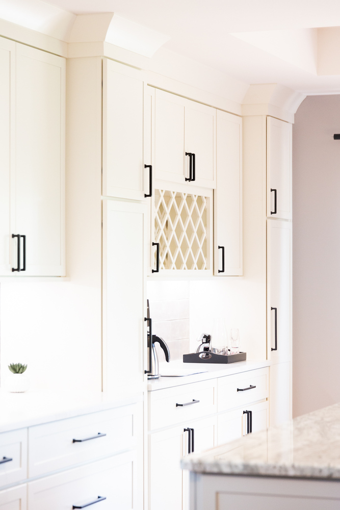 Custom white cabinetry with built-in wine rack in a luxury kitchen by Cabinet Creations in Bloomfield Hills, MI