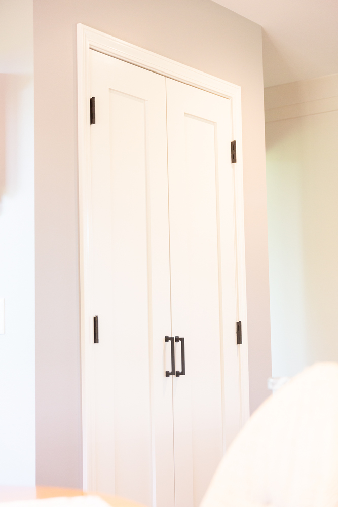 Minimalist white doors with contrasting black hinges and handles in a custom home by Cabinet Creations, Oakland County