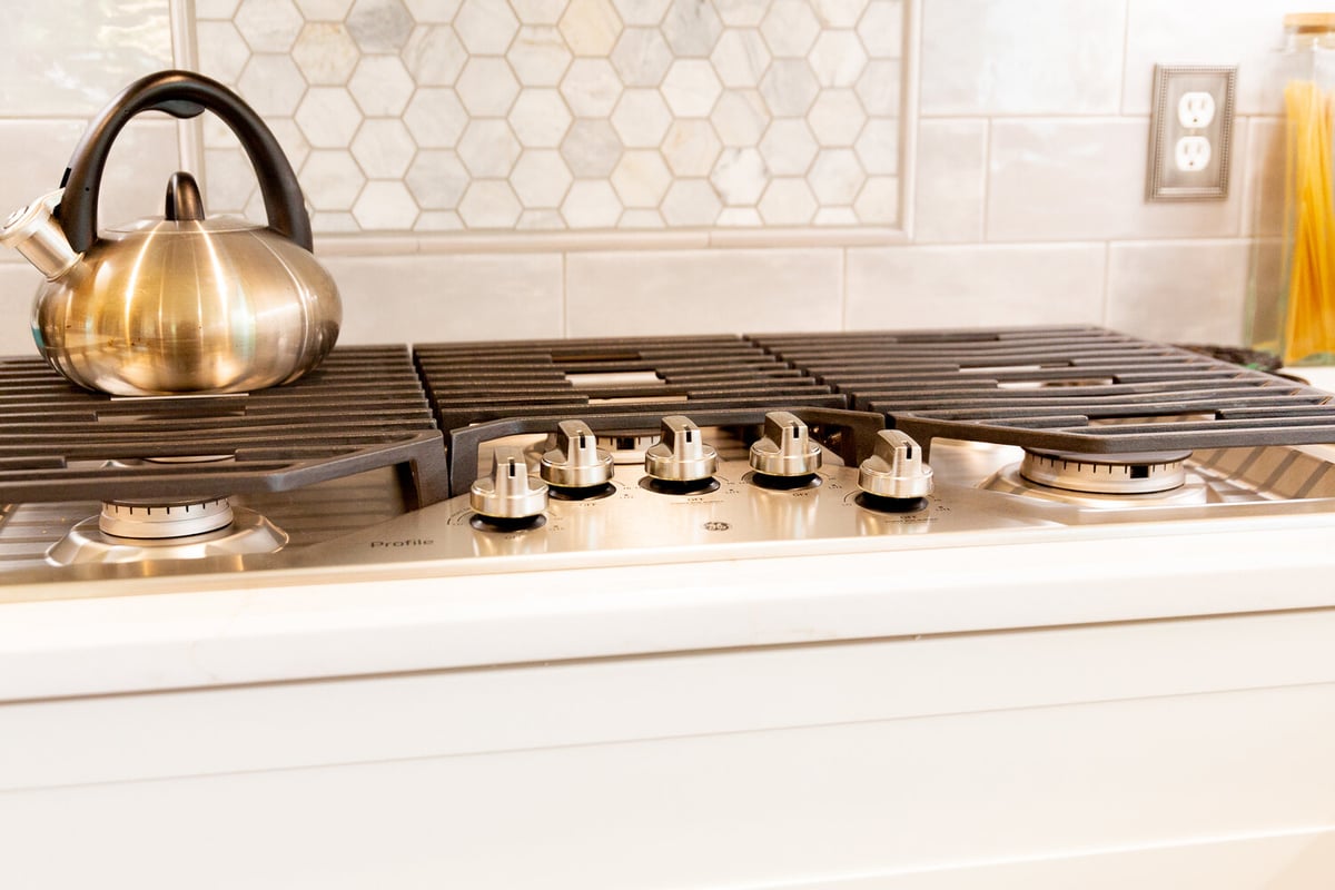 Sleek kitchen design with hexagon tile accent and stainless range by Cabinet Creations in Oakland County, MI.
