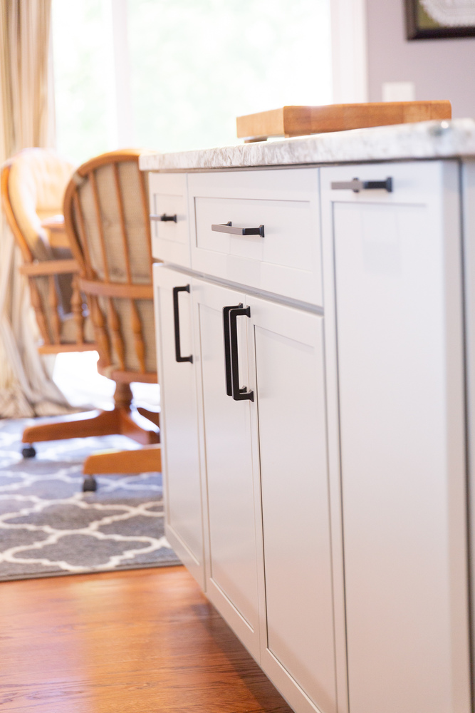 White kitchen island cabinets with black handles and wood floors by Cabinet Creations in Oakland County, MI