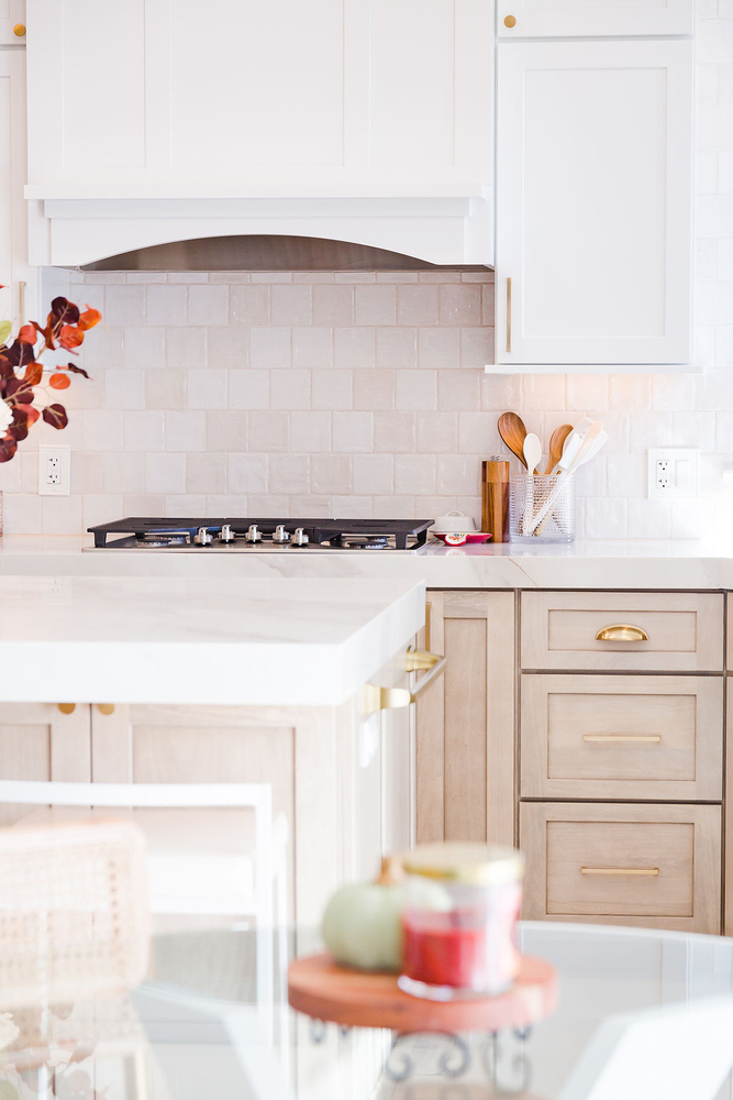White and wood cabinetry with a sleek cooktop and marble counters by Cabinet Creations, Oakland County, Michigan
