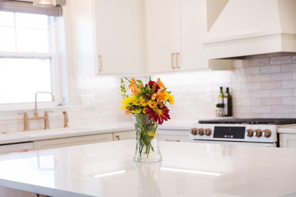 Bright kitchen island with quartz countertop and floral centerpiece by Cabinet Creations in Bloomfield Hills, MI