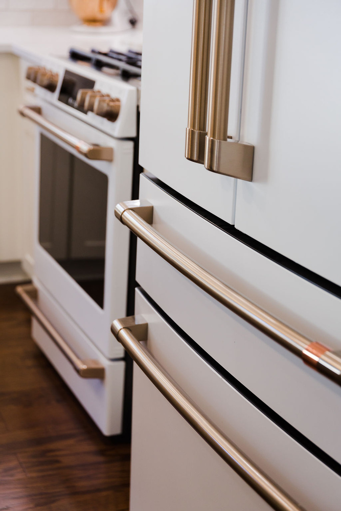 Close-up of gold hardware on refrigerator and range in a custom kitchen by Cabinet Creations in Michigan