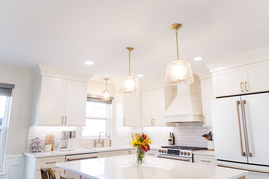 Custom kitchen with quartz island, pendant lighting, and white cabinetry by Cabinet Creations in Ferndale, MI