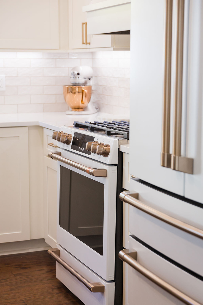 Custom white gas range and cabinetry with brass hardware by Cabinet Creations in Ferndale, MI