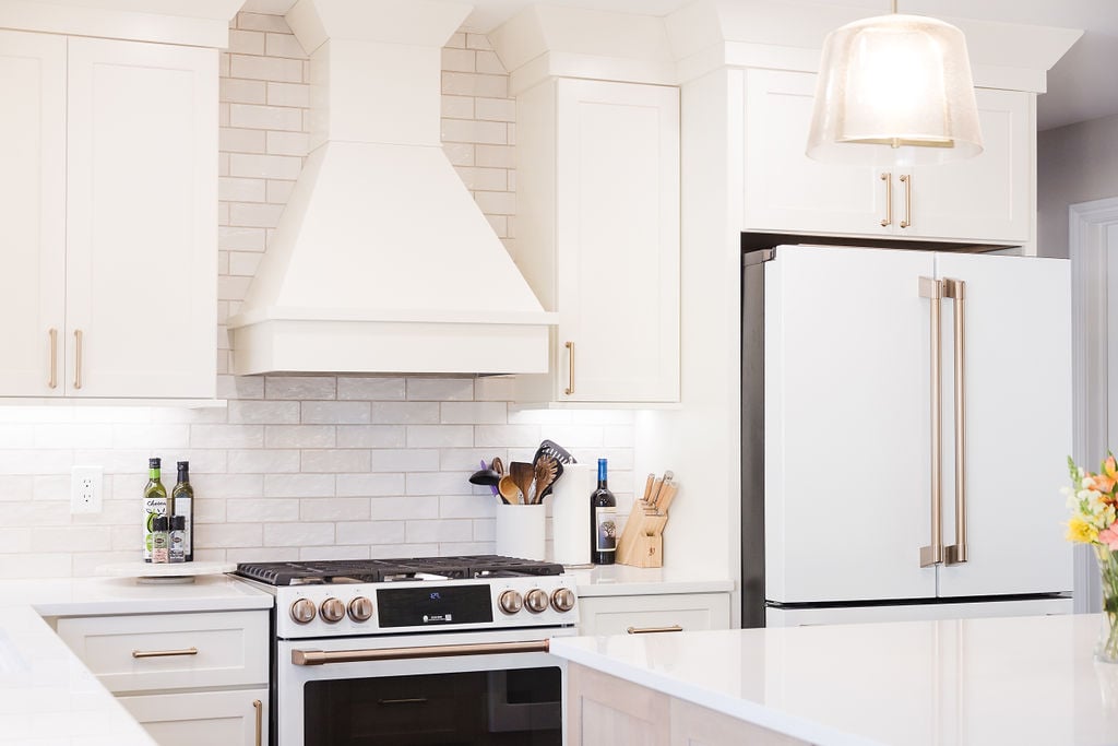 Custom white kitchen with modern vent hood and brass accents by Cabinet Creations in Oakland County, MI