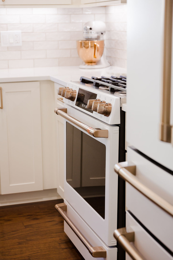 Elegant kitchen range and cabinetry design with gold finishes in Oakland County, MI