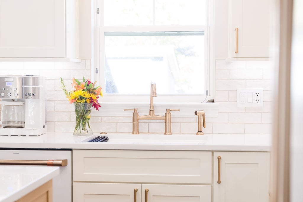 Kitchen sink area with gold faucet and floral arrangement by Cabinet Creations in Oakland County, MI