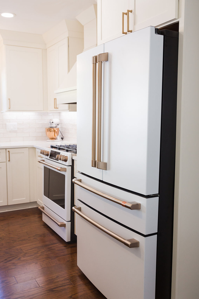 Modern white refrigerator and cabinetry with brass hardware by Cabinet Creations in Waterford Township, MI