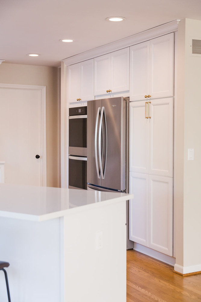 Built-in refrigerator and white shaker cabinets with gold hardware in custom kitchen by Cabinet Creations, Oakland County, MI
