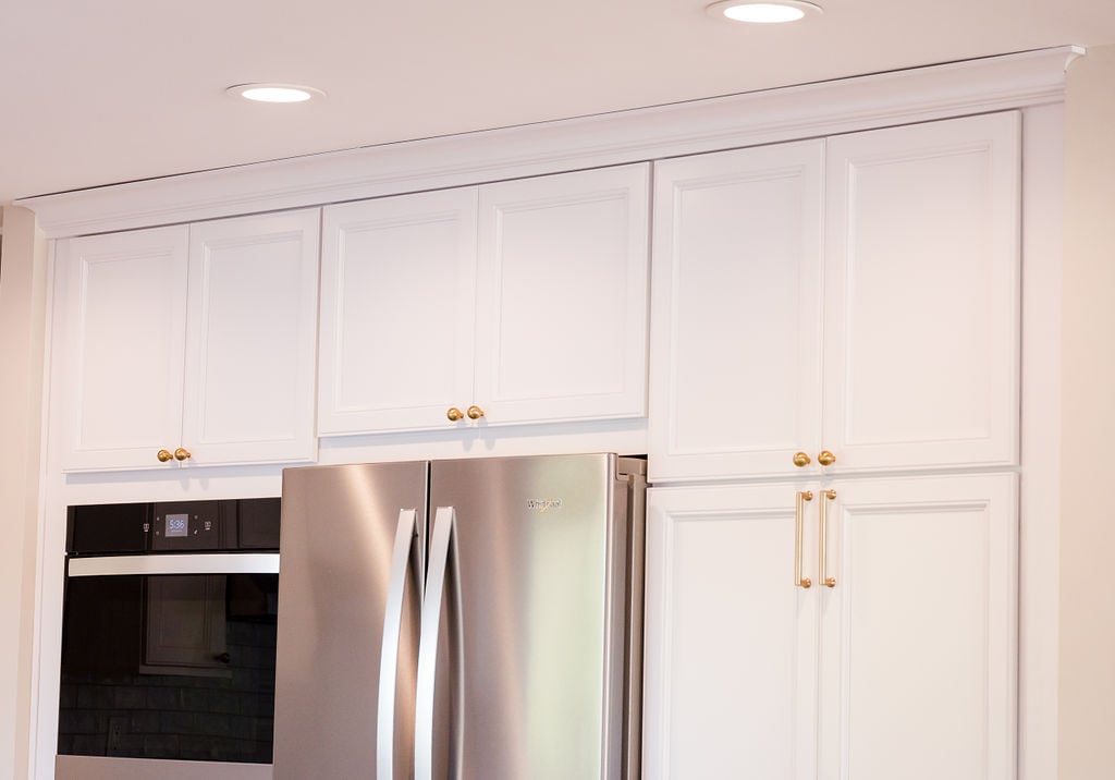 Built-in wall oven and refrigerator framed by custom cabinets in Oakland County home by Cabinet Creations