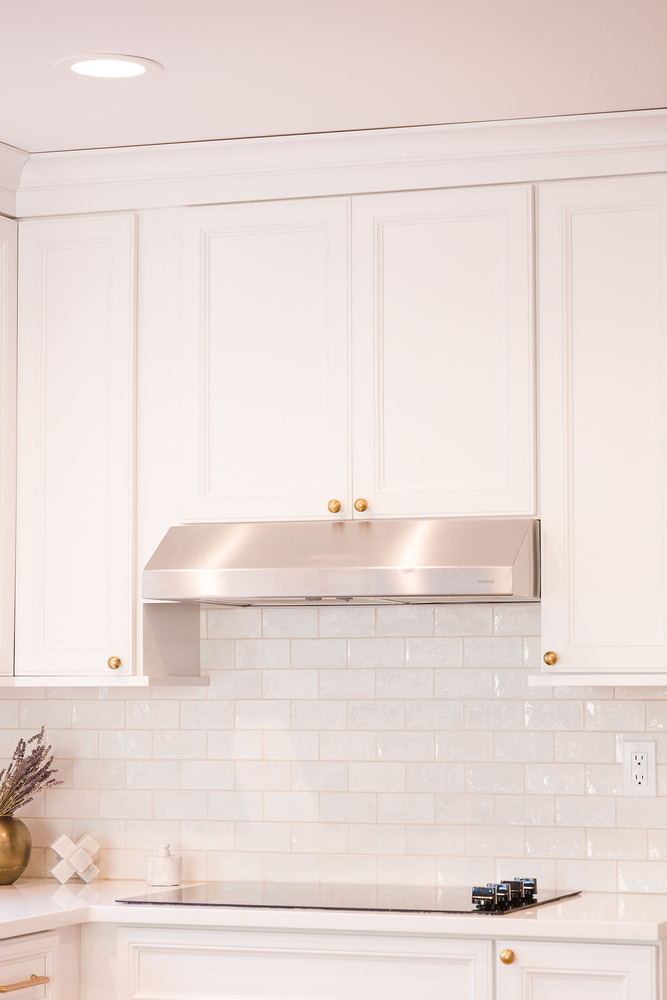 Close-up of stainless steel range hood and white subway tile backsplash in a custom Waterford Township kitchen by Cabinet Creations