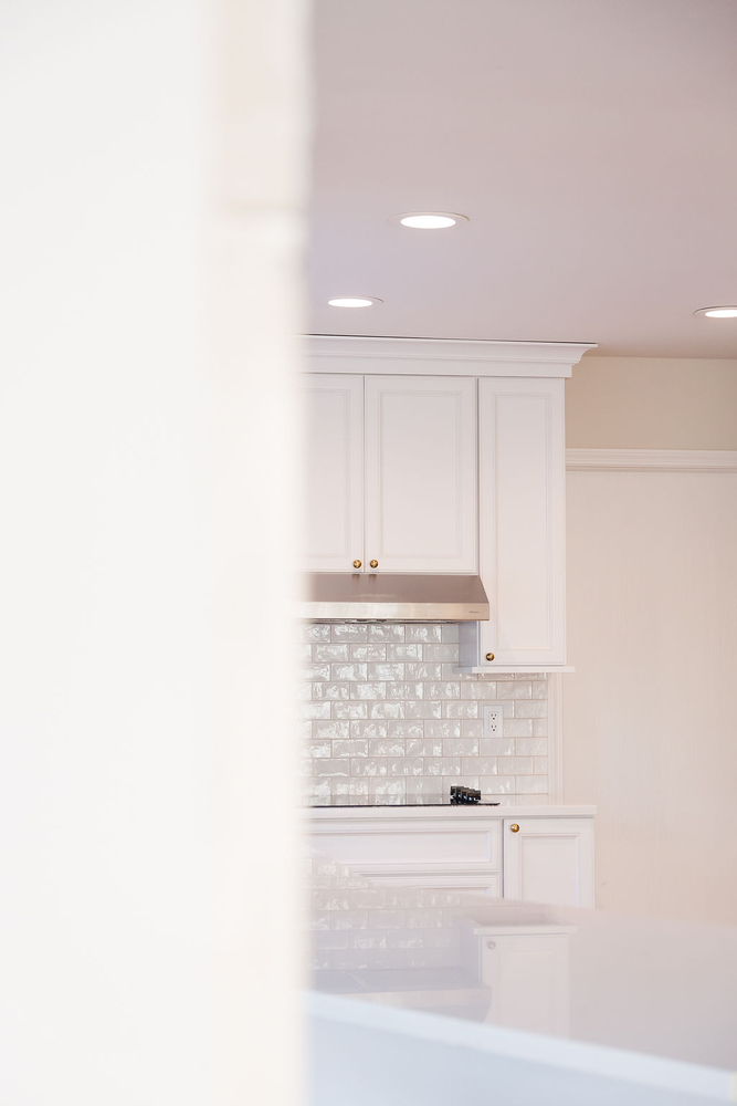 Contemporary custom kitchen detail with high-gloss backsplash and soft recessed lighting in Ferndale, MI