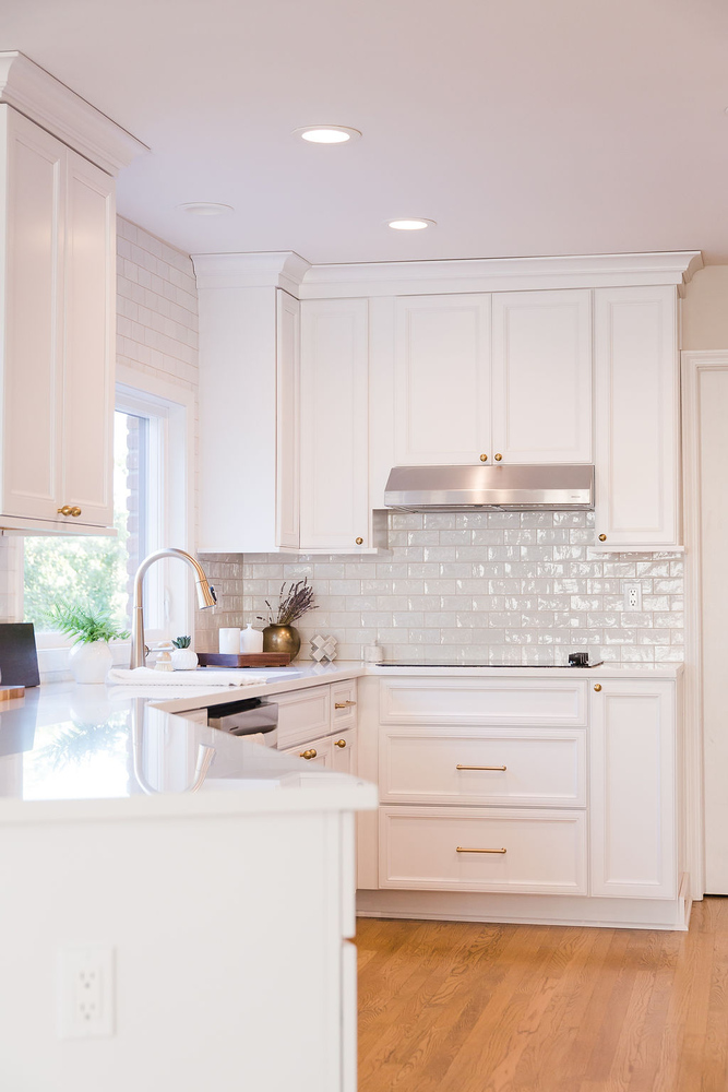 Corner view of white kitchen with stainless hood and tile backsplash in a custom home by Cabinet Creations, Oakland County, MI
