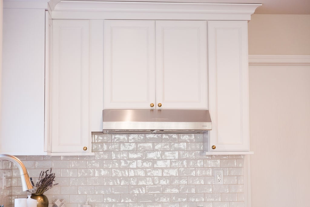 Custom kitchen cabinetry and stainless hood framed by glossy subway tile backsplash by Cabinet Creations in Oakland County, MI