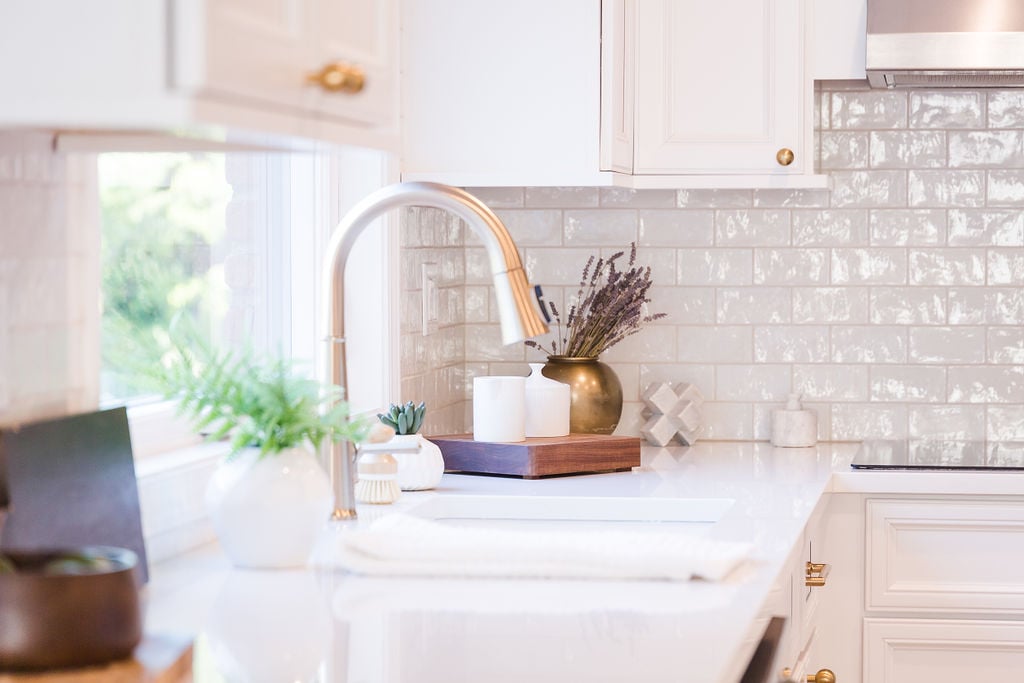 Elegant kitchen sink area with brass faucet and natural light by Cabinet Creations in Oakland County, MI
