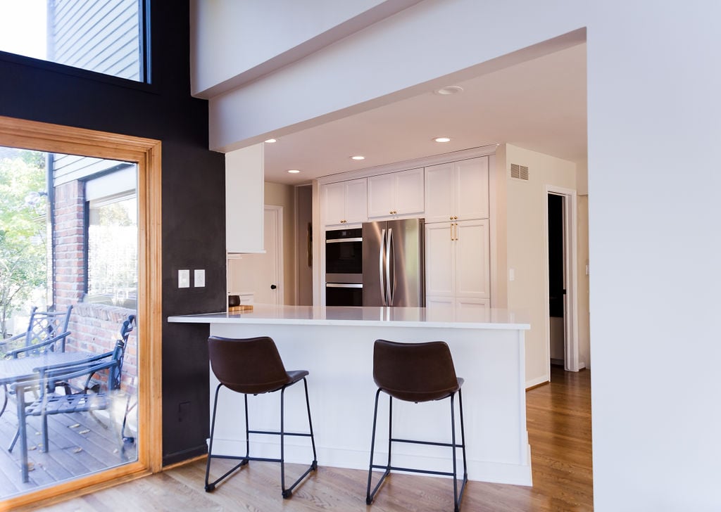 Michigan custom home kitchen with white cabinets and dark accent wall by Cabinet Creations