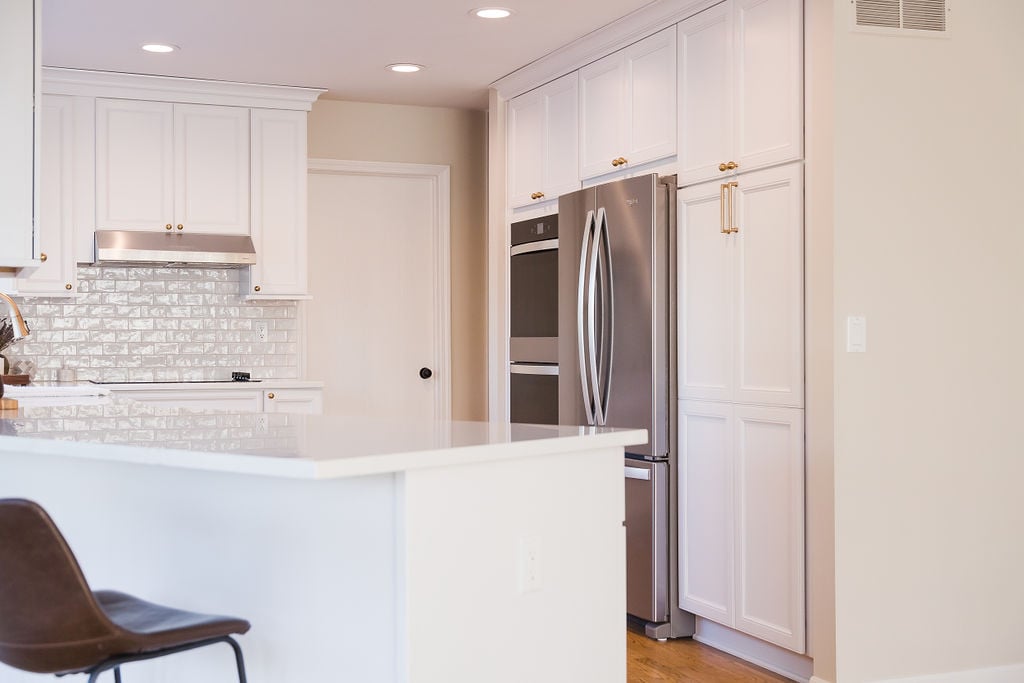 Side view of white kitchen cabinetry and stainless appliances in Oakland County home by Cabinet Creations