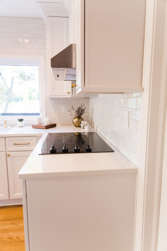 Sleek black electric cooktop on white quartz countertop in a custom kitchen by Cabinet Creations, Oakland County, MI