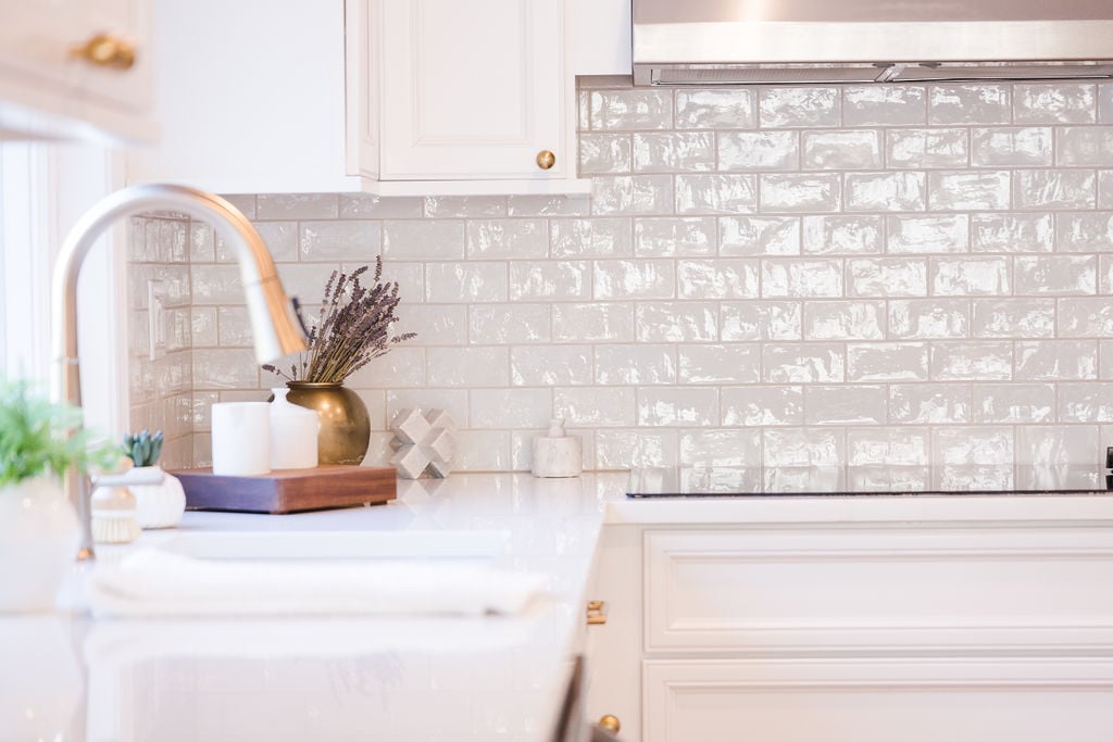 White quartz countertops with brass faucet and styled accessories in Oakland County custom kitchen by Cabinet Creations
