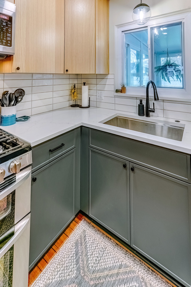 Kitchen sink corner with matte green base cabinets and white quartz counters in Waterford, MI by Cabinet Creations