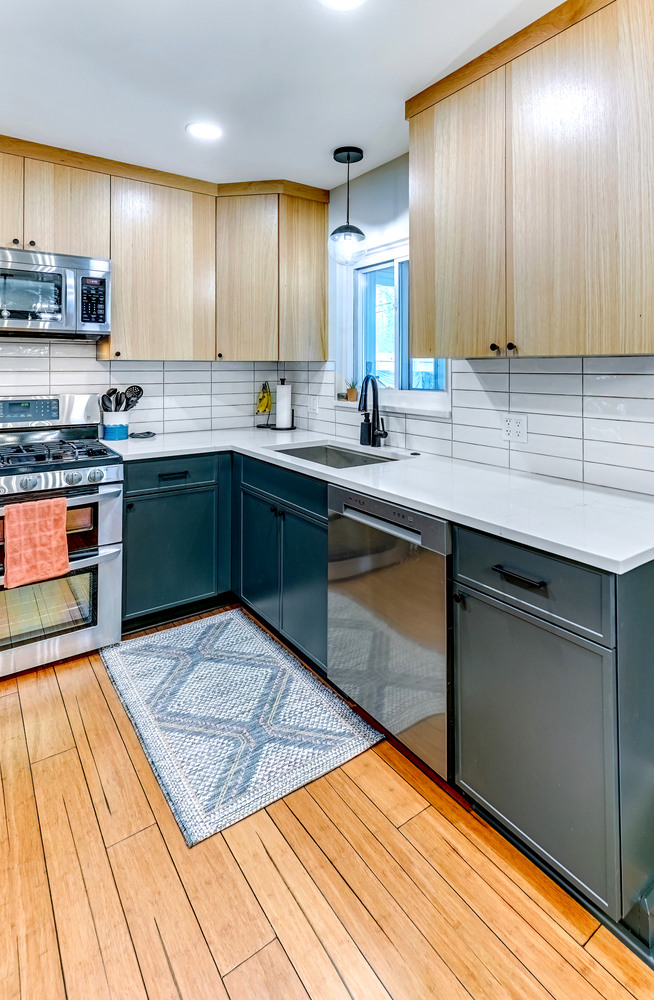 Modern kitchen cabinetry in Oakland County home featuring deep green lower cabinets and clean finishes by Cabinet Creations