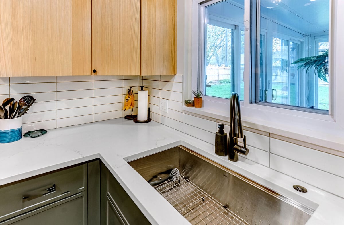 Side view of sink area with large stainless basin and light backsplash by Cabinet Creations in Waterford, MI