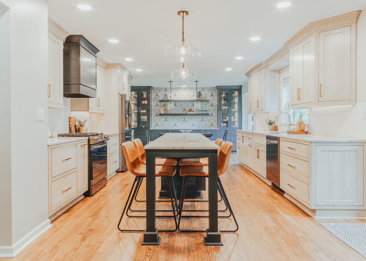 Custom kitchen design by Cabinet Creations in Clarkston with light cabinetry, black range hood, and hardwood floors