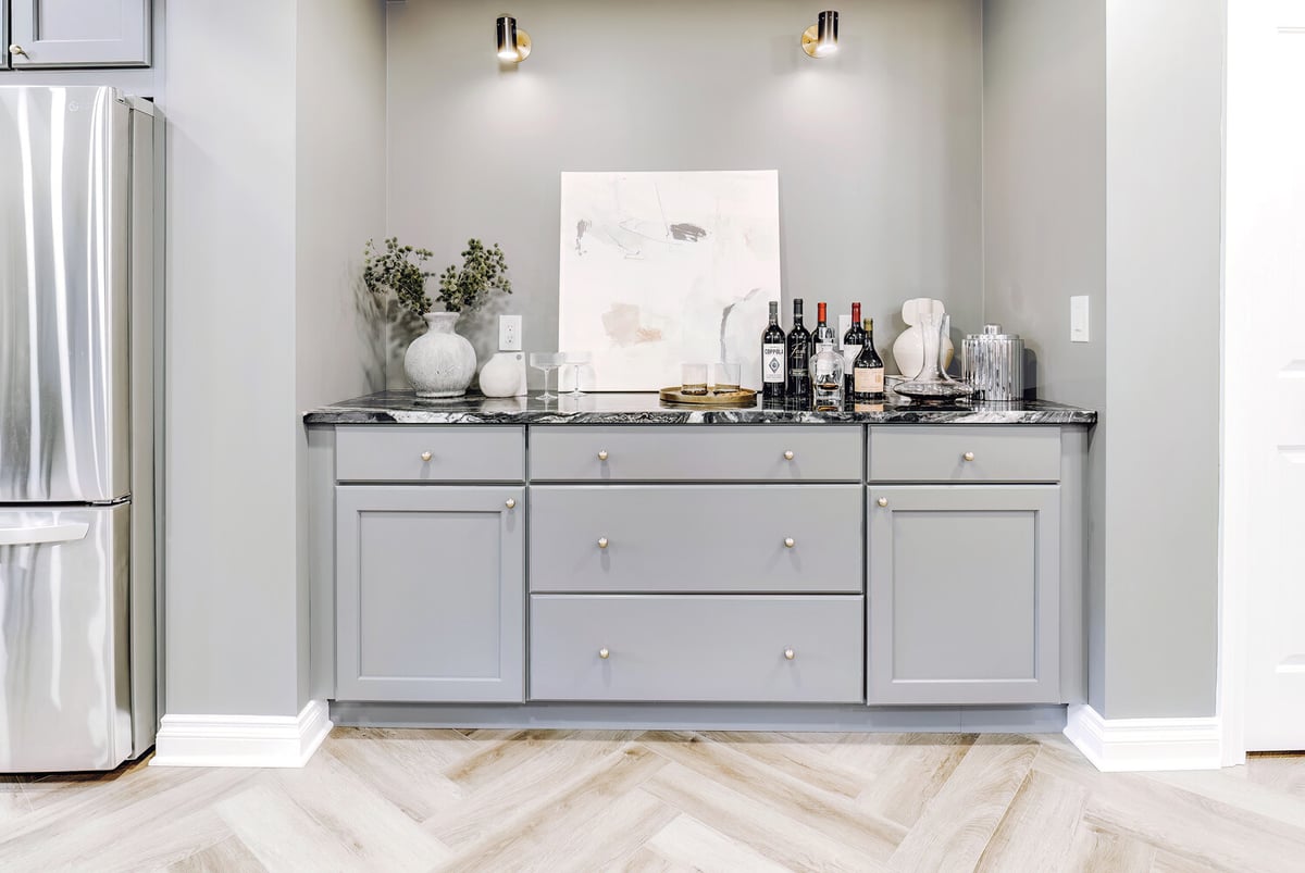 Basement bar area in Clarkston, MI custom home by Cabinet Creations featuring marble countertops and modern pendant lights