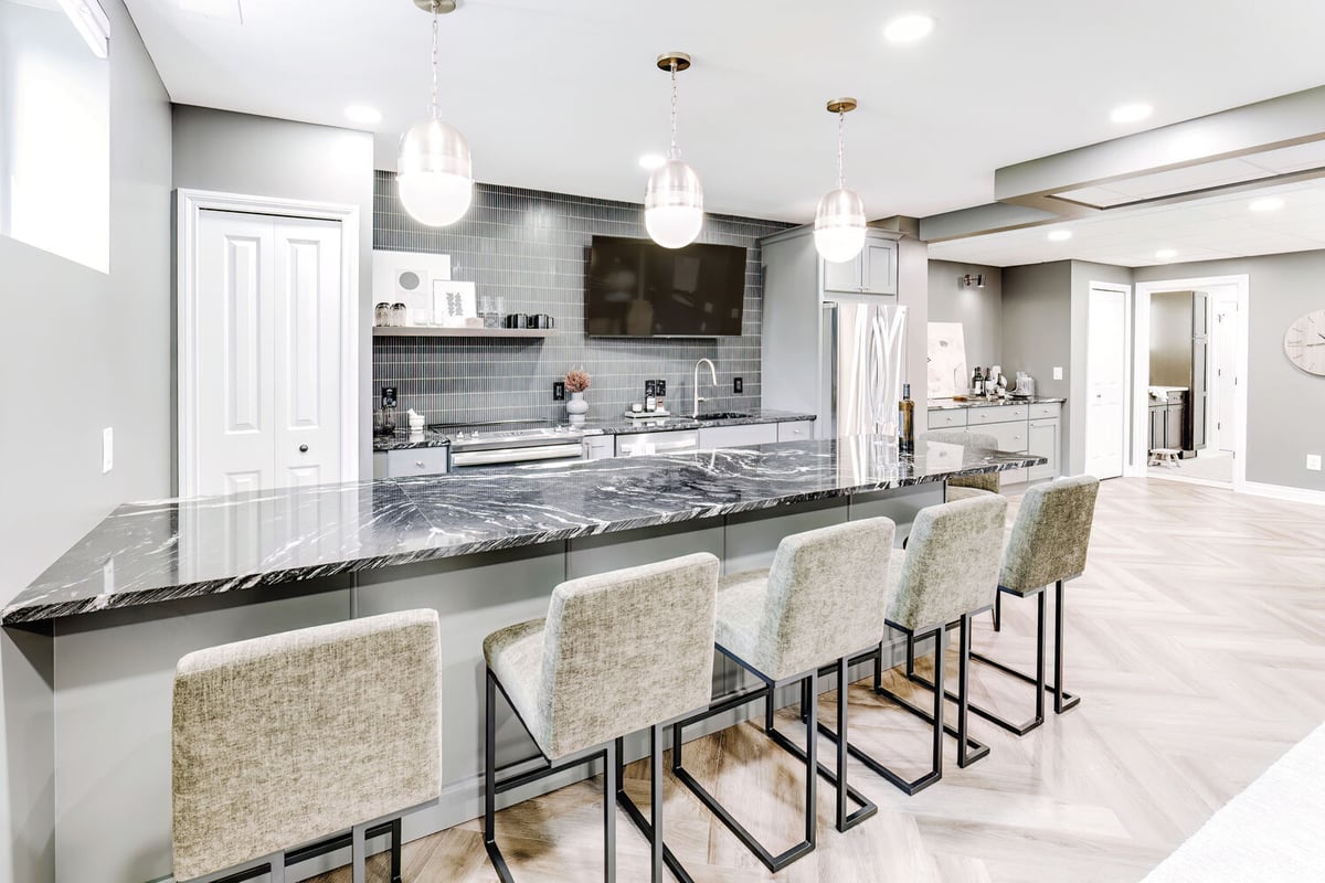 Cabinet Creations bar island with upholstered seating and tiled backsplash in Clarkston basement remodel