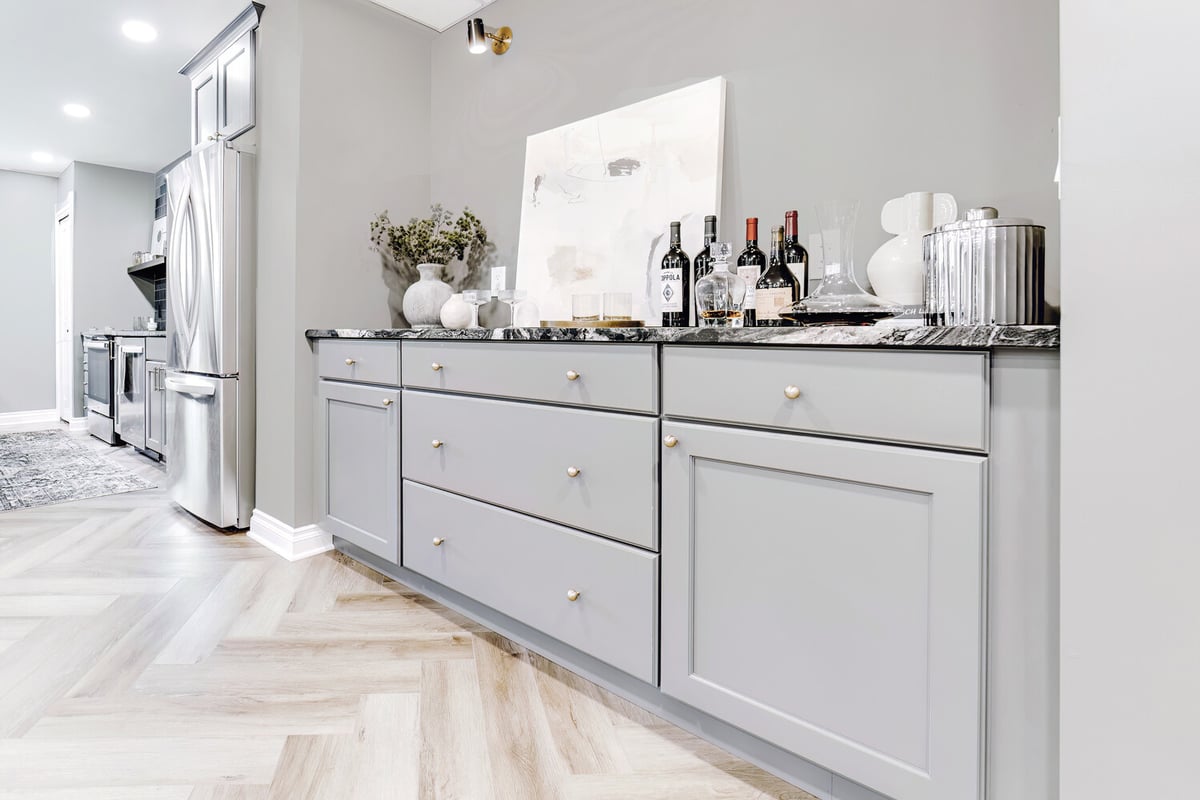 Full view of Clarkston custom home basement bar by Cabinet Creations with gray cabinets and natural light