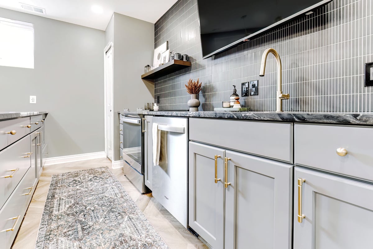 Gray cabinetry and brass faucet detail in Clarkston basement kitchen by Cabinet Creations