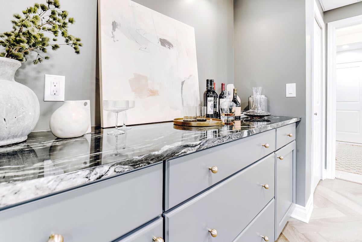 Side angle of Clarkston basement bar by Cabinet Creations featuring decorative tray and wine bottle display