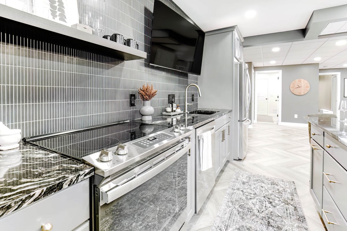 Sleek basement kitchen space in Clarkston custom home by Cabinet Creations with black tile backsplash