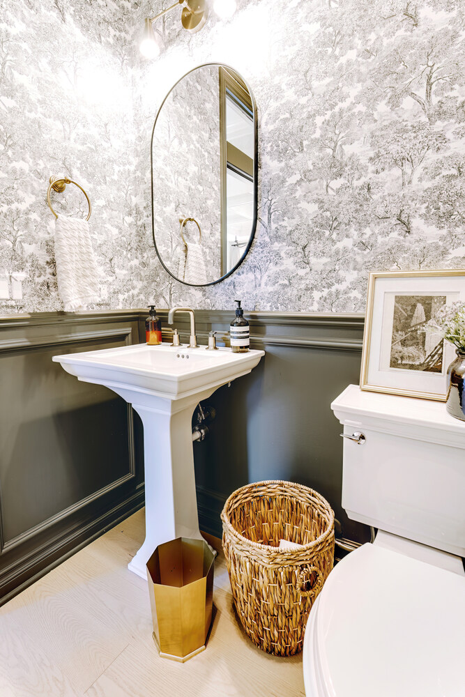 Luxury half bathroom with oval mirror and brass accents in Waterford Township, MI