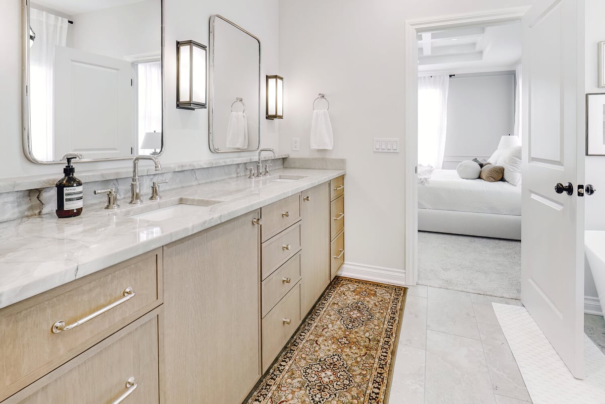 Dual vanity design with marble counters and entry to bedroom in a custom home by Cabinet Creations in Michigan
