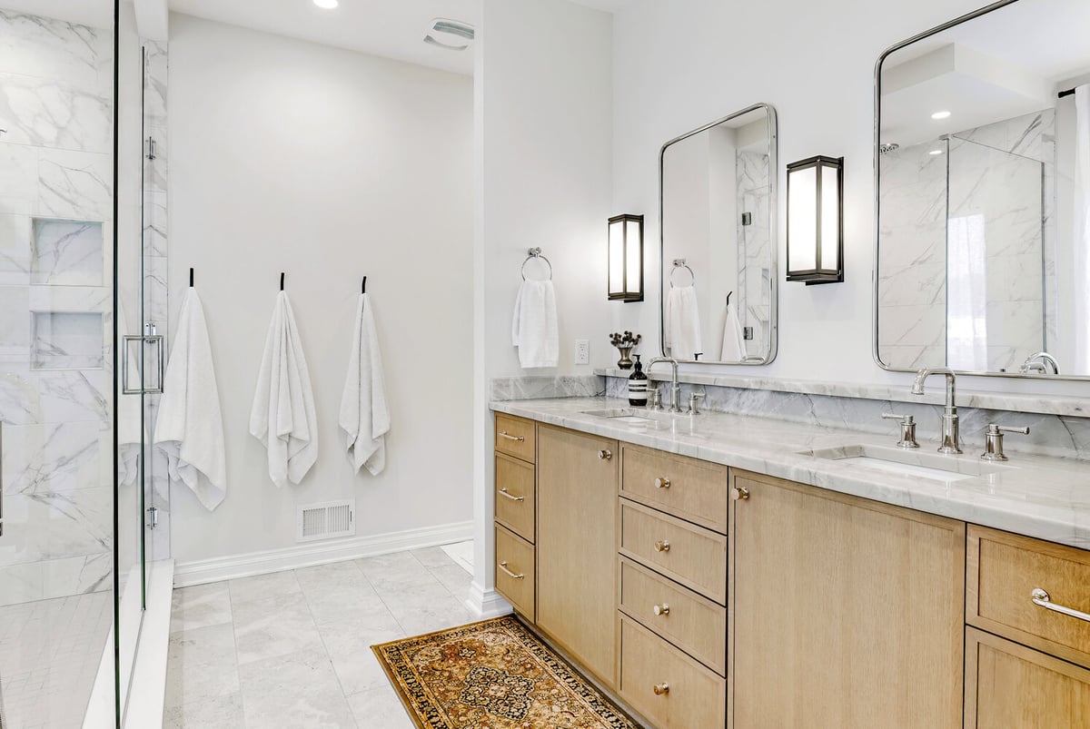 Dual-sink vanity with framed mirrors and modern lighting in a Waterford Township custom home