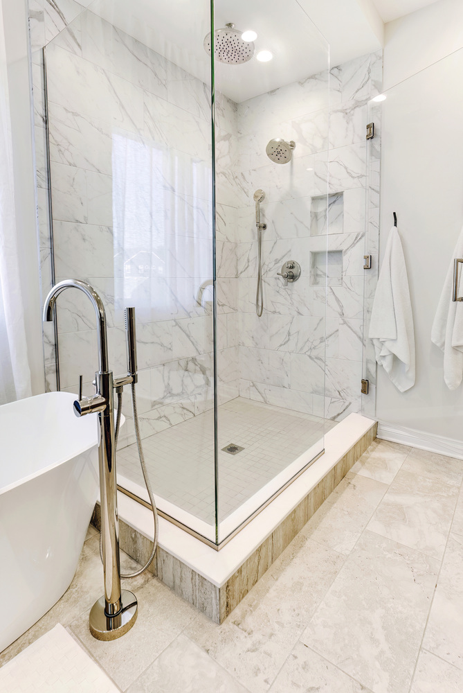 Frameless glass shower with marble tile installed by Cabinet Creations in a custom home in Waterford, MI