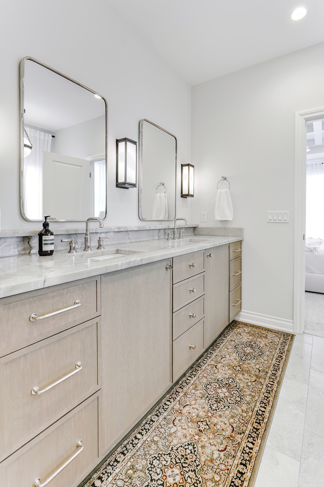 Long dual-sink bathroom vanity with chrome fixtures and light wood cabinetry in a Birmingham, MI custom home