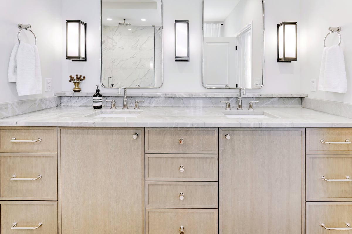 Wide double-sink vanity with light wood cabinetry in a custom home bathroom by Cabinet Creations in Troy, MI