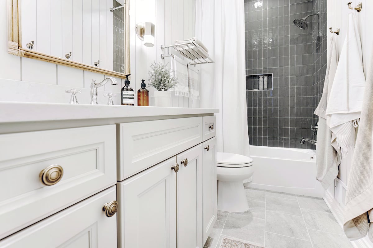 Custom bathroom view with white cabinetry and black tiled shower in Clarkston by Cabinet Creations