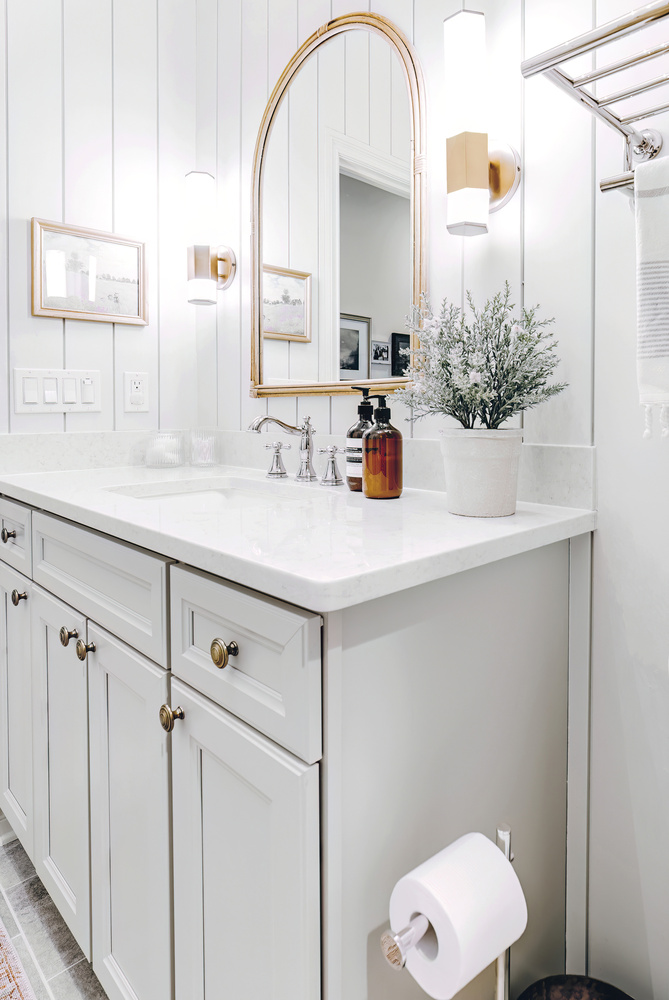 White shiplap bathroom wall with arched mirror and decor in Clarkston by Cabinet Creations